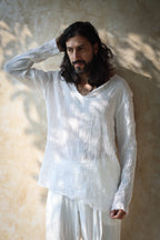 A model wearing the Kian Linen Shirt and matching drawstring pants in a crisp white tone, embodying effortless bohemian elegance. This lightweight, breathable outfit is made from natural fabrics, perfect for slow fashion enthusiasts. From Bird of Paradise, Bali boho clothings