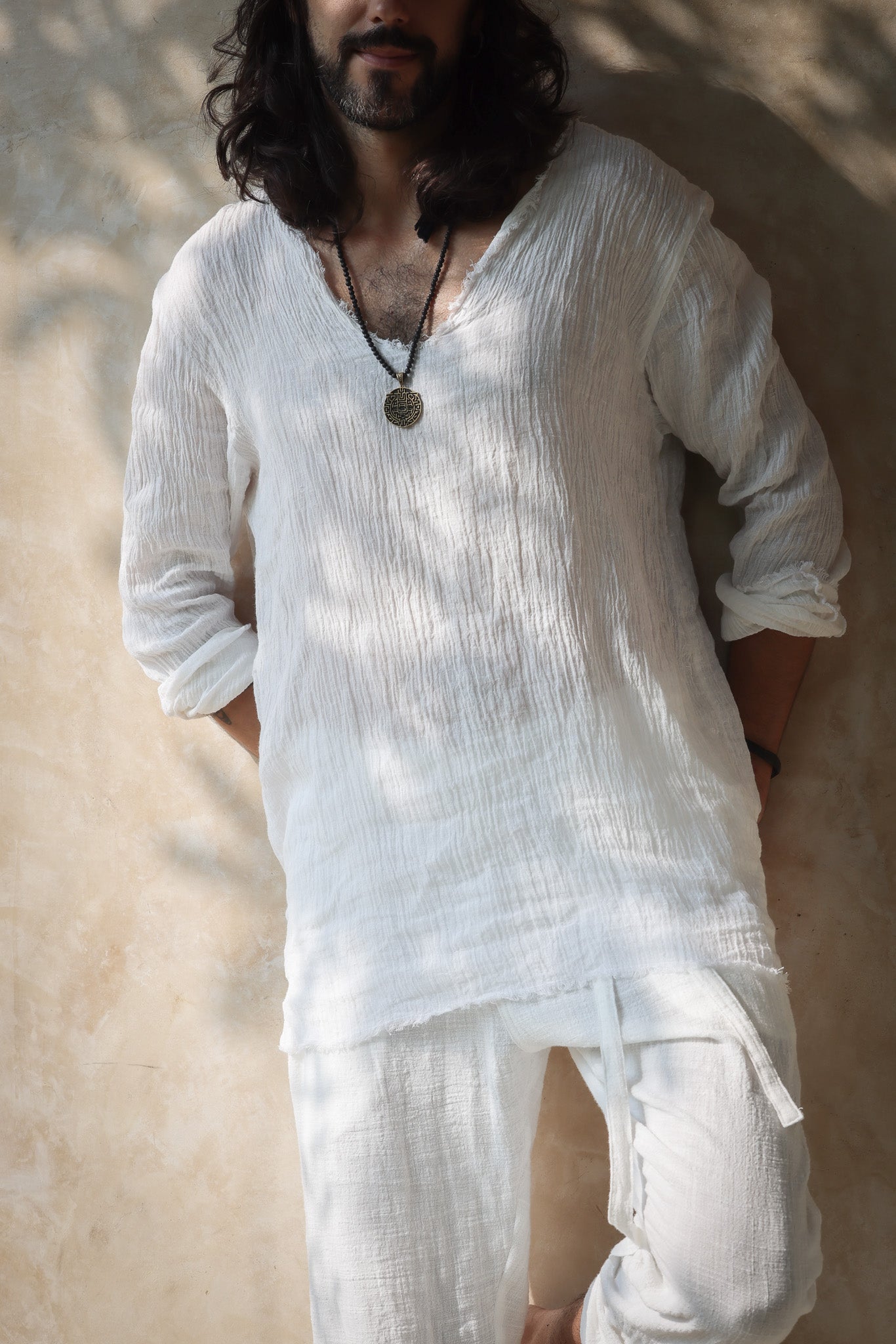 A model wearing the Kian Linen Shirt and matching drawstring pants in a crisp white tone, embodying effortless bohemian elegance. This lightweight, breathable outfit is made from natural fabrics, perfect for slow fashion enthusiasts. From Bird of Paradise, Bali boho clothings