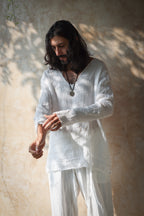 A model wearing the Kian Linen Shirt and matching drawstring pants in a crisp white tone, embodying effortless bohemian elegance. This lightweight, breathable outfit is made from natural fabrics, perfect for slow fashion enthusiasts. From Bird of Paradise, Bali boho clothings