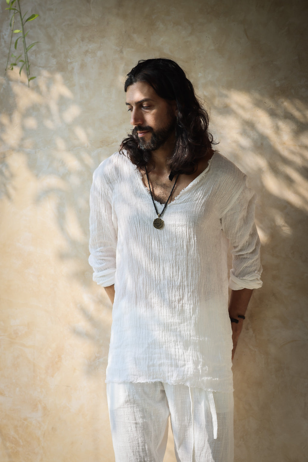 A model wearing the Kian Linen Shirt and matching drawstring pants in a crisp white tone, embodying effortless bohemian elegance. This lightweight, breathable outfit is made from natural fabrics, perfect for slow fashion enthusiasts. From Bird of Paradise, Bali boho clothings