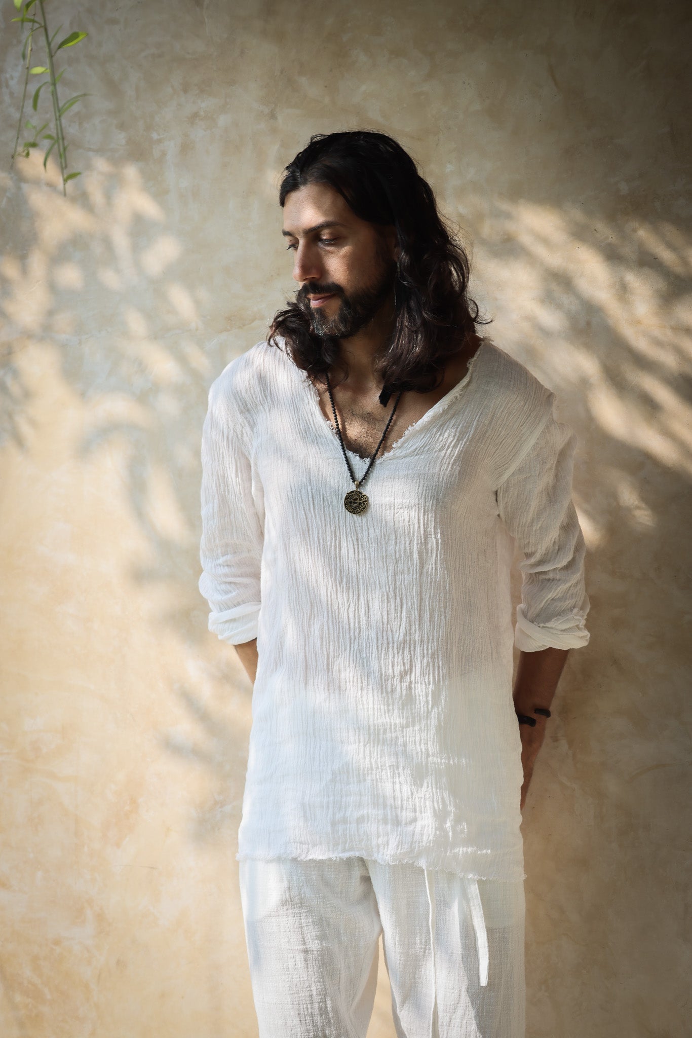 A model wearing the Kian Linen Shirt and matching drawstring pants in a crisp white tone, embodying effortless bohemian elegance. This lightweight, breathable outfit is made from natural fabrics, perfect for slow fashion enthusiasts. From Bird of Paradise, Bali boho clothings