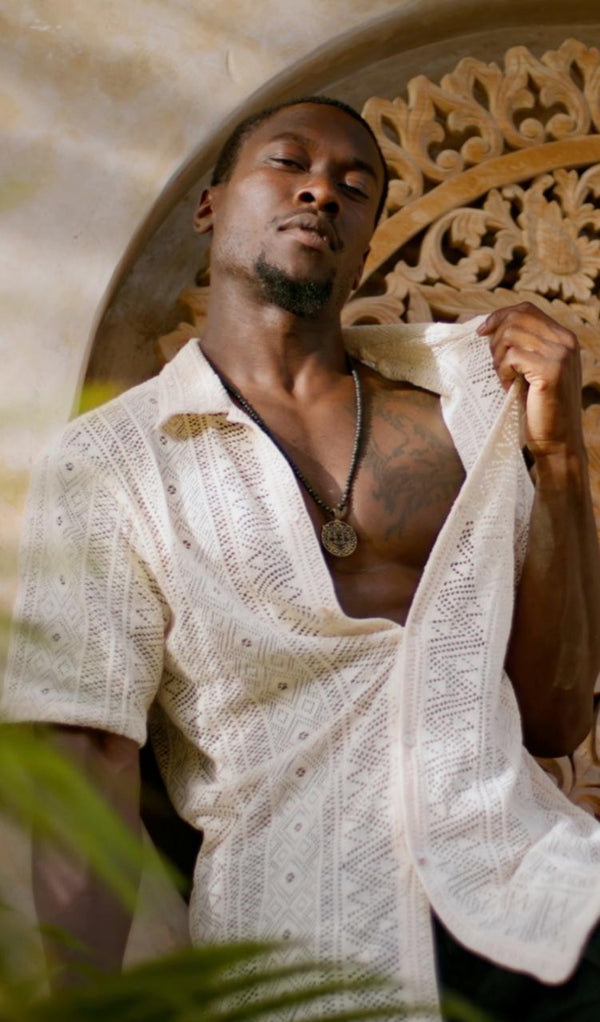Man wearing the Yuto Shirt from Bird of Paradise, a handcrafted short-sleeve lace shirt with intricate patterns. This bohemian-inspired, designer sustainable fashion piece embodies Bali boho clothing and mindful luxury