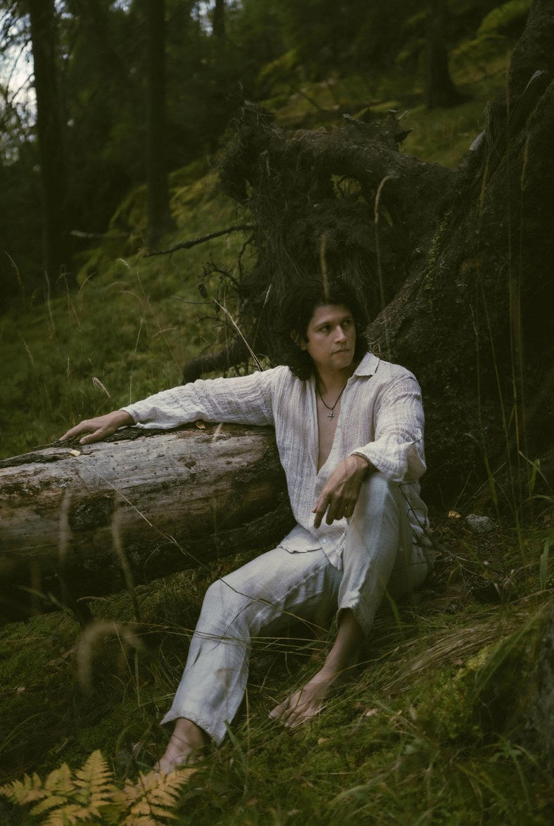 Kairos Pants worn with a linen shirt, seated against a fallen tree