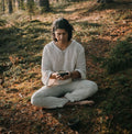 Man seated in the forest wearing the Serat handloom linen pullover shirt