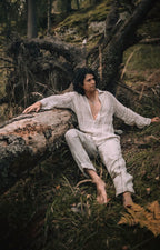 Man wearing the Tenun open-weave linen shirt, reclining on a fallen tree