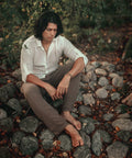 Man wearing the Udara handloom linen and cotton shirt, seated on river stones